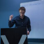 Home Man with eyeglasses presenting with marker in front of a whiteboard indoors, emphasizing productivity.