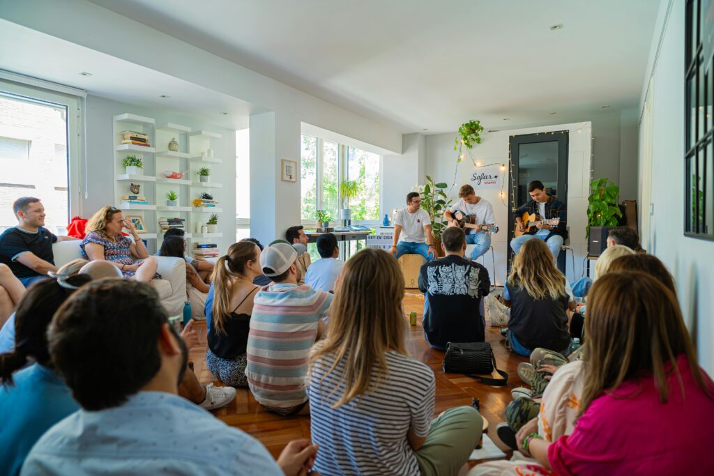 Live acoustic band performing in a cozy apartment to an attentive audience.